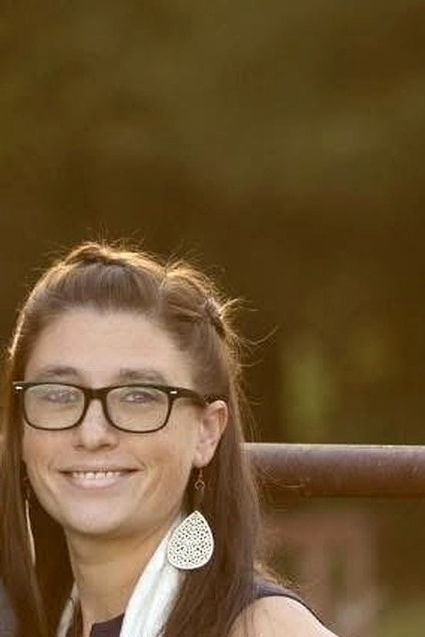 Alyse Adams smiling outdoors near farm fencing